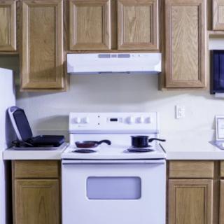 A modern kitchen setup with a stove, oven, and wooden cabinets.