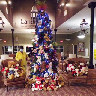 A beautifully decorated Christmas tree surrounded by stuffed animals in a cozy lobby.