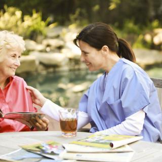 A nurse providing care to an elderly woman outside.
