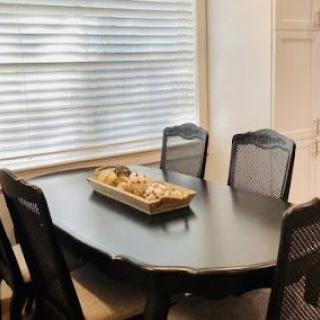 A cozy dining area featuring a dark oval table with matching chairs, adorned with a decorative centerpiece, near a window with blinds.
