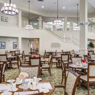 A spacious and elegant dining area with neatly arranged tables and chairs, illuminated by chandeliers.