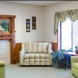 A cozy living room with a striped armchair, decorative fireplace, and a large window with curtains.
