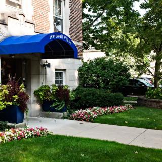 A well-maintained building entrance with a blue awning and landscaped greenery.