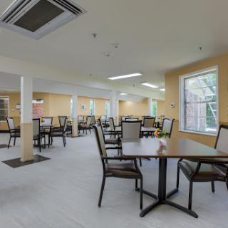 A spacious and modern dining area with neatly arranged tables and chairs, illuminated by natural light.