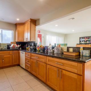 A spacious kitchen with wooden cabinets and a black countertop, featuring modern appliances.