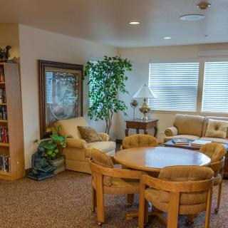 A cozy living room with comfortable seating, a round table, and a bookshelf against the wall.