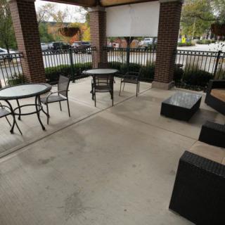 An outdoor patio with tables and chairs under a covered area.