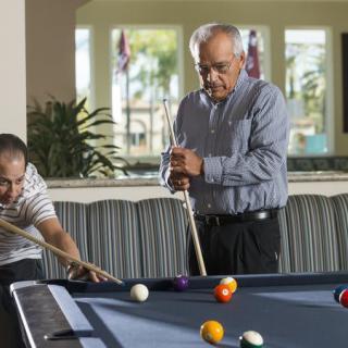 Two people playing billiards indoors.