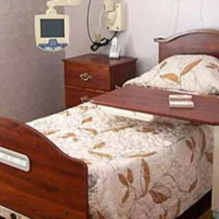 A hospital room with a neatly made bed and medical equipment.