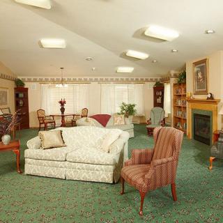 A cozy traditional living room with a sofa, armchairs, and a fireplace.