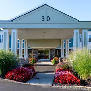 A building entrance with well-maintained landscaping and colorful flowers.