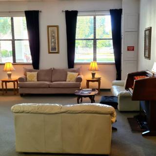 A cozy living room with sofas, lamps, and large windows.