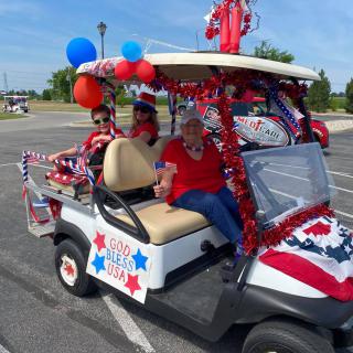 A festive golf cart decorated in red, white, and blue with balloons, ready for a parade.