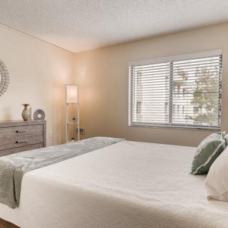 A minimalist and modern bedroom with a neatly made bed, dresser, and decorative items.