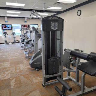 A well-equipped gym featuring various exercise machines, including a cable machine and weight benches.