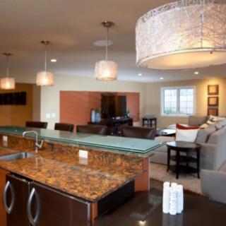 A modern open-plan kitchen and living room with stylish lighting and a granite countertop.