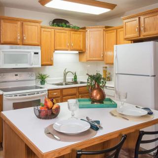 A cozy kitchen with wooden cabinets and modern appliances, featuring a small dining area with decorative elements.