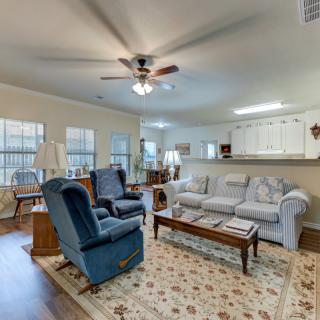 A cozy living room with a sofa, armchairs, and a coffee table under a ceiling fan.