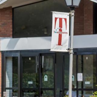 The image shows the entrance of a building with a university banner displaying a logo.