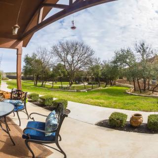 A sunny patio overlooking a lush garden with trees and a well-maintained lawn.