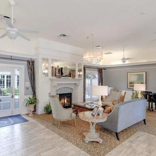 A spacious living room with elegant decor, featuring a fireplace and chandelier.