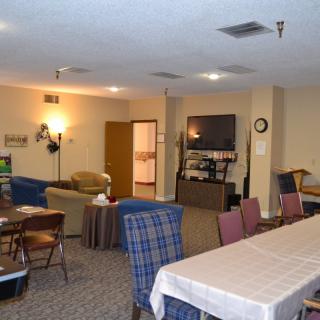 A cozy living and dining area featuring various seating options, a television, and warm lighting.