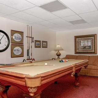 A cozy game room featuring a pool table, wall decor, and comfortable seating.