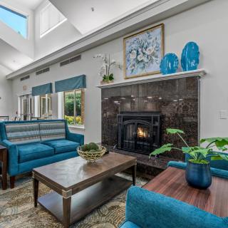 A modern living room featuring blue furniture and a cozy fireplace, highlighted by natural light from a skylight.
