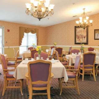 A well-decorated dining room with elegant chandeliers, neatly arranged tables and chairs, creating a cozy and inviting atmosphere.