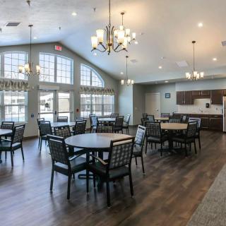 A spacious dining area with multiple tables and chairs, featuring large windows and elegant chandeliers.