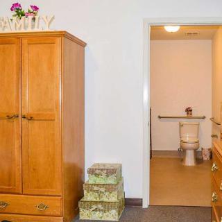 A cozy bedroom with a wooden wardrobe and an adjacent view into a bathroom.