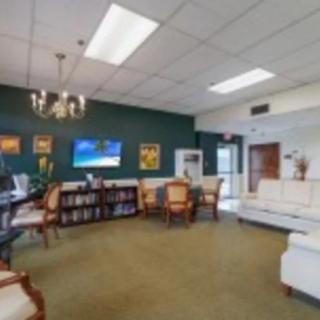 A comfortable waiting room with sofas, chairs, a television, and decorative elements.