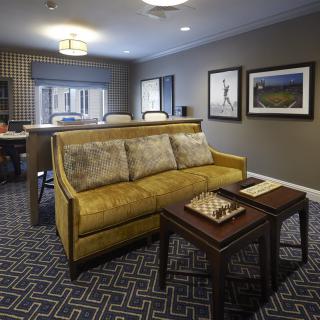 A cozy living room featuring a yellow sofa, coffee tables, and framed artwork on the walls.