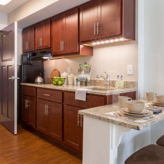 A modern kitchen with wood cabinets and a cozy dining area.