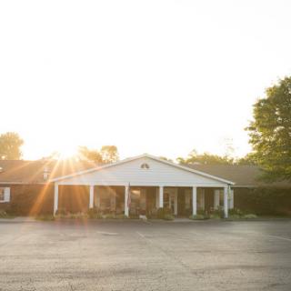 A serene sunrise illuminates the front of a charming building, showcasing its welcoming architecture.