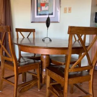 A wooden dining set with a round table and four chairs in an elegantly designed room.