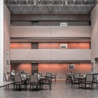 A modern dining area with tables and chairs, featuring a high ceiling and contemporary design.