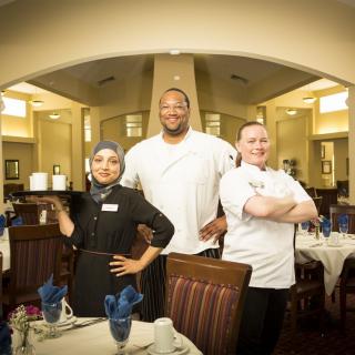 A team of chefs standing proudly in a restaurant dining area.