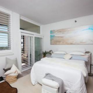 A modern minimalist bedroom with a double bed, white walls, and simple decor.