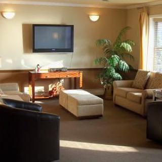 A cozy living room with comfortable seating, a wall-mounted television, and a decorative plant.