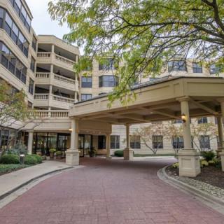 A view of a building entrance with a covered driveway surrounded by trees.