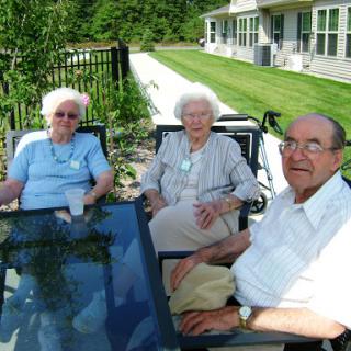 A group of three elderly individuals enjoying a sunny day outdoors.