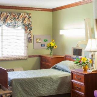 A cozy bedroom with a single bed, bedside table, and decorative floral arrangements.