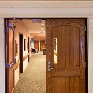 A view of a wooden door leading into a carpeted hallway.