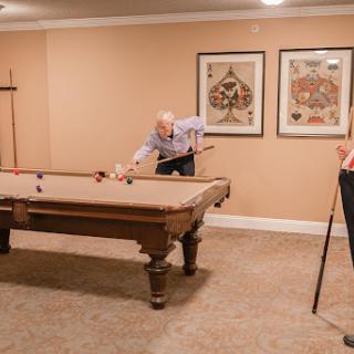 Two people enjoying a game of billiards in a cozy indoor setting.