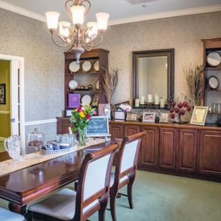 A well-decorated dining room with a wooden table and chairs, ornate cabinets, and a chandelier.