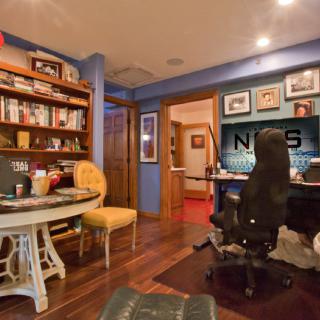 A cozy home office with a bookshelf, desk, and computer.
