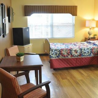 A cozy bedroom with a bed, table, and chairs by a window.