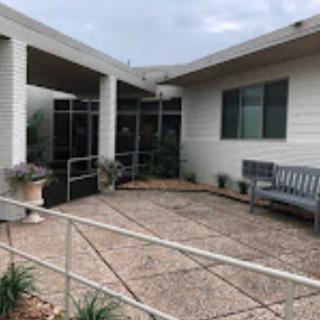 A building entrance with a bench, potted plants, and a ramp leading to the doorway.