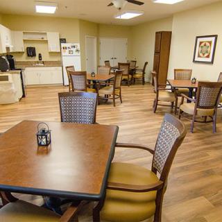 A cozy dining area with several tables and chairs, adjacent to a kitchen space.